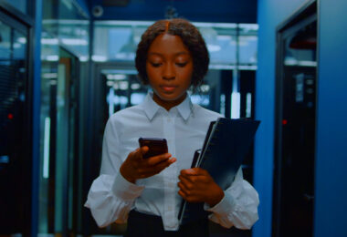 Woman looking at mobile while walking though computer room