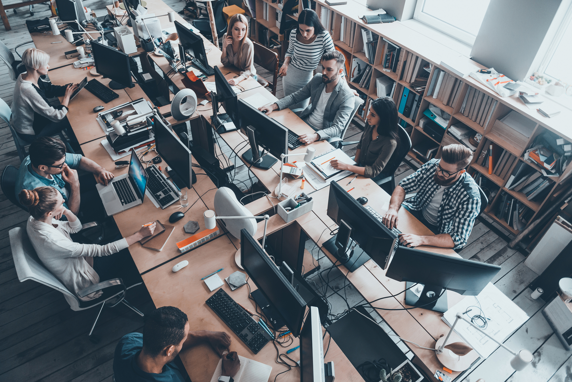 Top view of group of young business people working together reading Encryption Report while sitting at the large office desk
