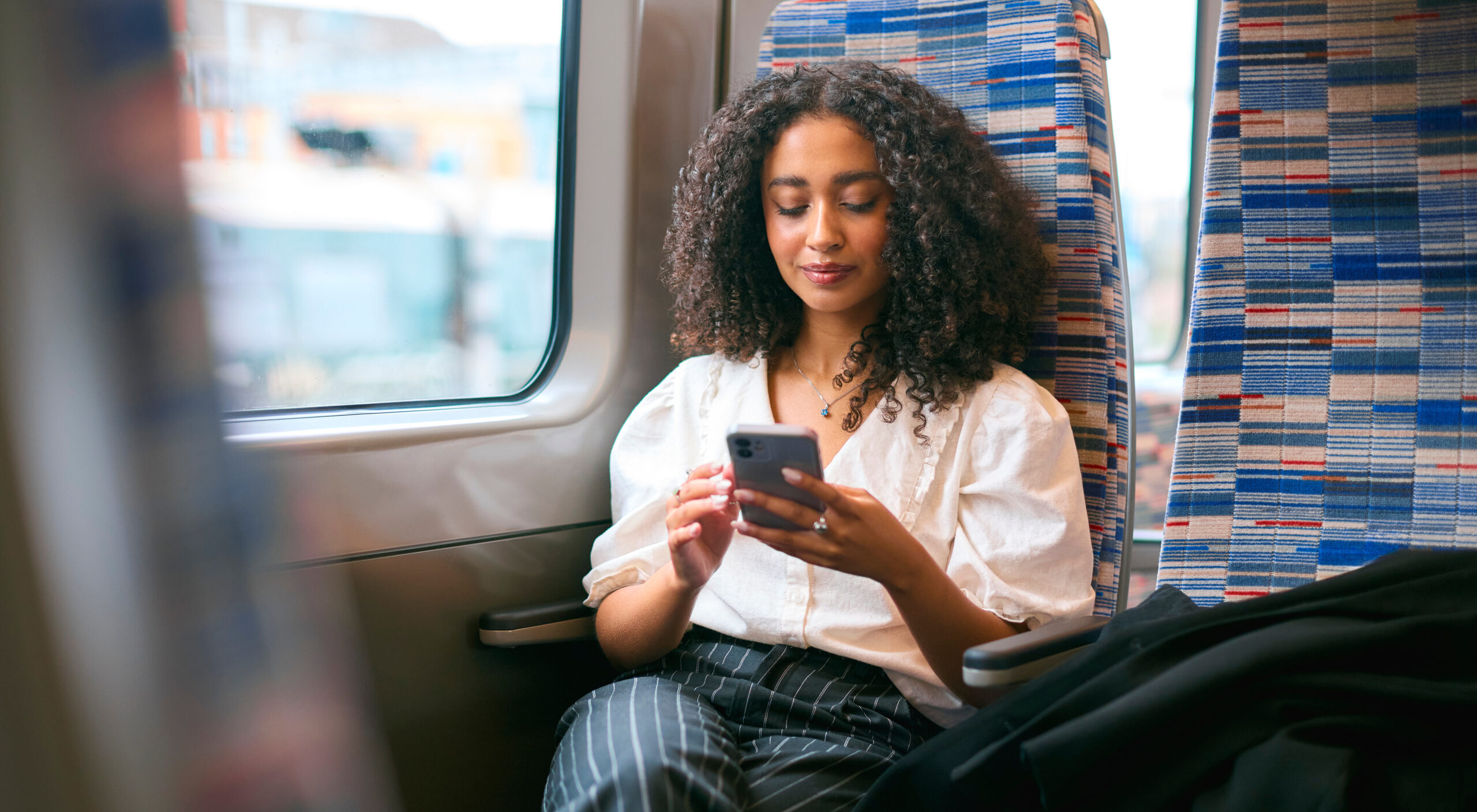 Businesswoman Commuting To Work On Train Sitting Checking Messages Or Social Media On Mobile Phone