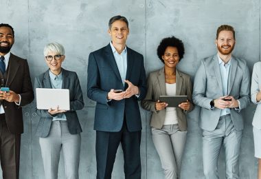 Portrait of young and senior business people having a meeting and using technology mobile phone, laptop and tablet in the office